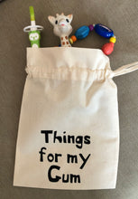 Load image into Gallery viewer, A canvas drawstring bag with Things for my gum printed on the front and baby teething toys poking out of the top.